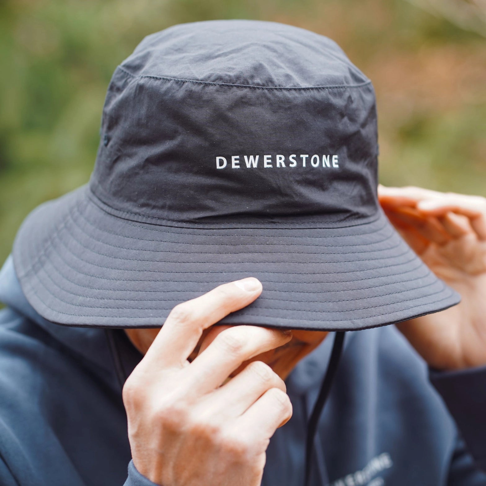 Traveler wearing the black Dewerstone recycled bucket hat – front view
