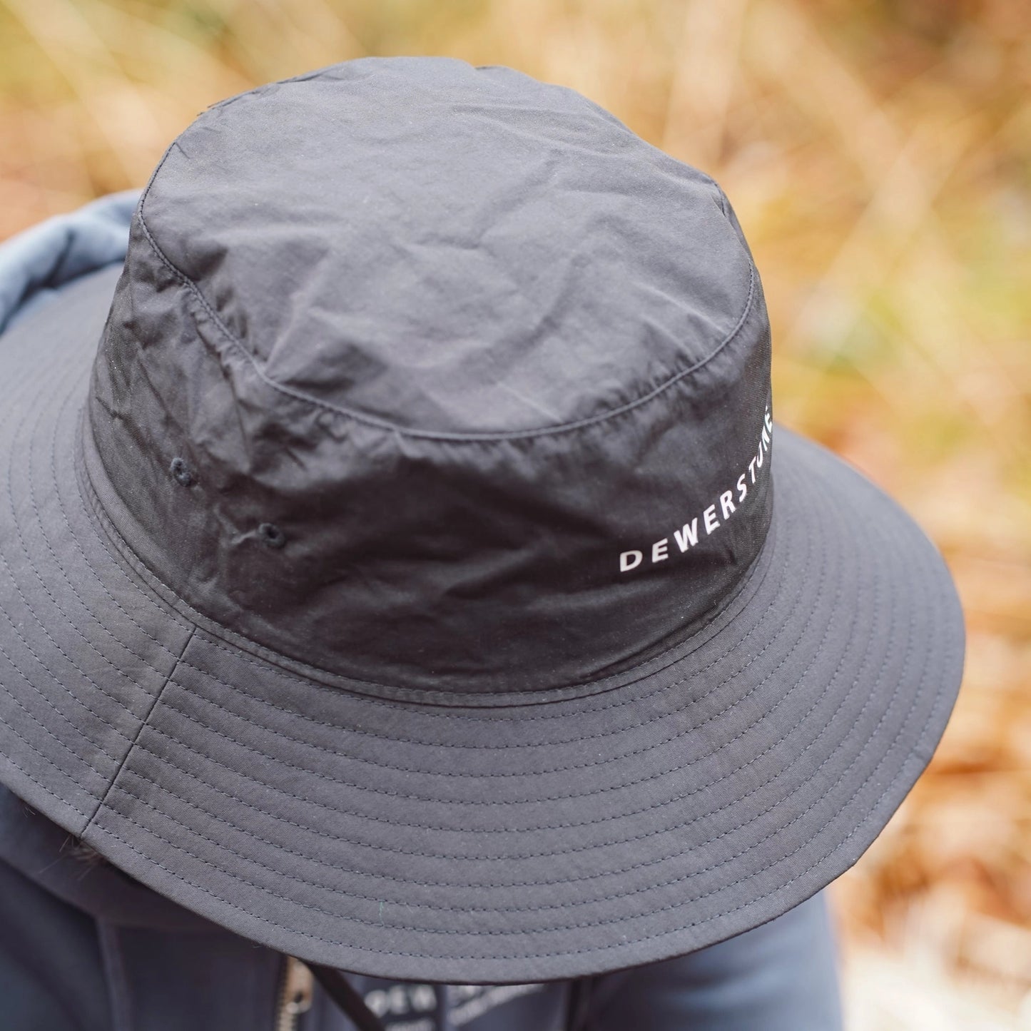 Black quick-dry bucket hat placed outdoors – ideal for travel and hiking